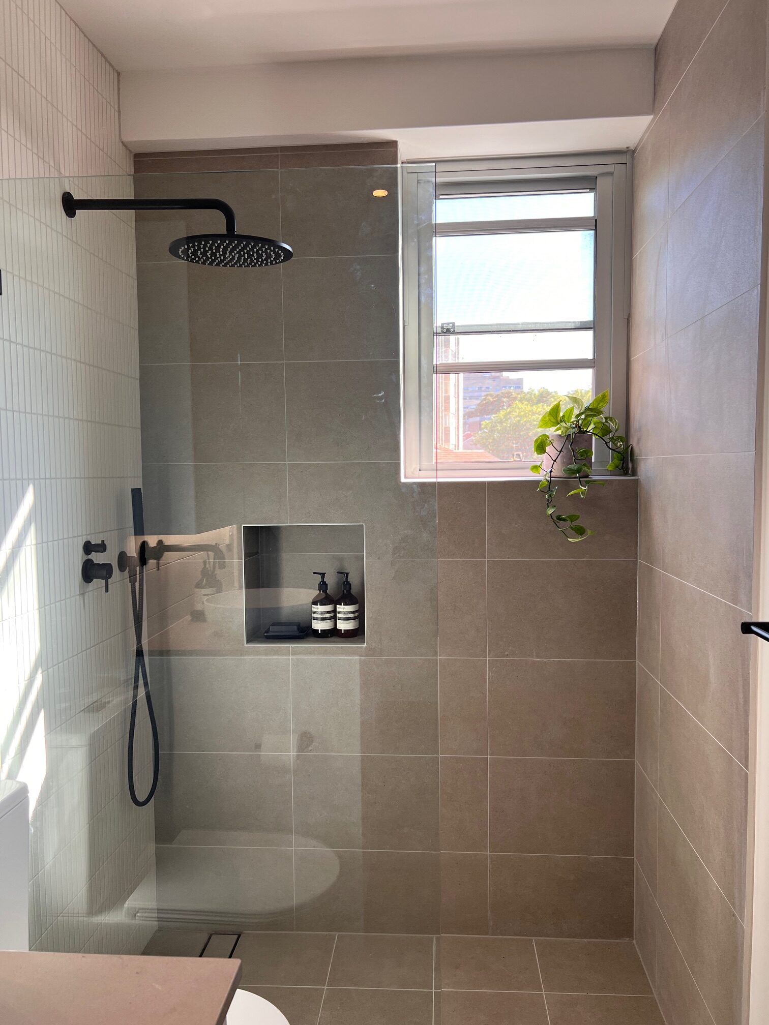 Walk-in shower with grey tiles and recessed niche