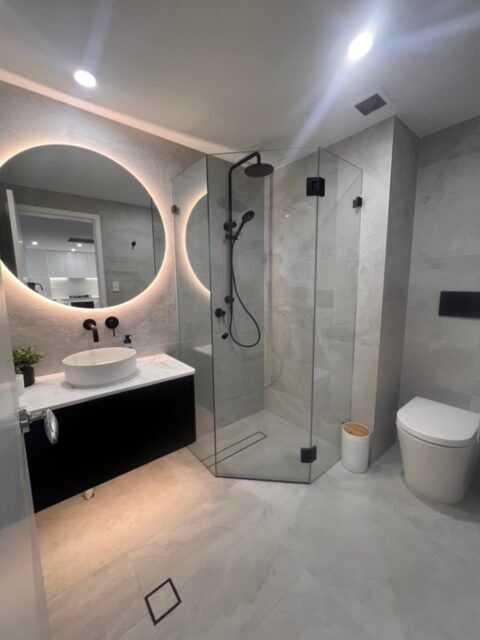 Bathroom with illuminated round mirror and shower